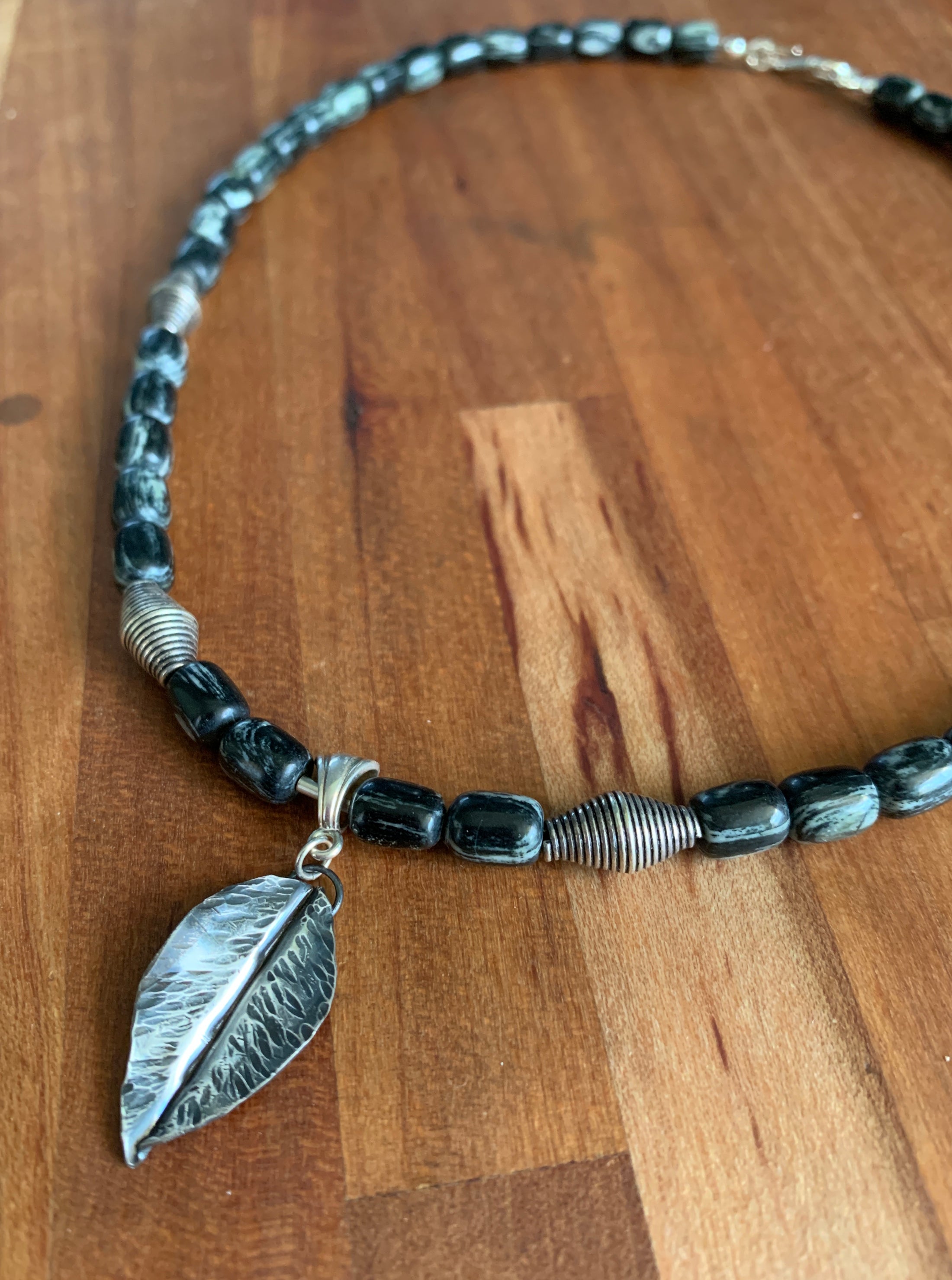 handforged sterling silver leaf pendant necklace on silver mist jasper beads, displayed on butcher block
